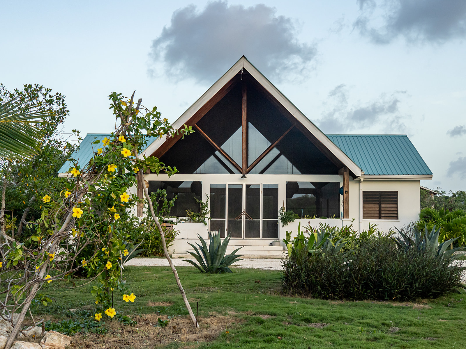 Belizima’s main building with a turquoise roof and flowering garden.